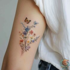 a woman's arm with flowers and butterflies tattoo on the left side of her arm