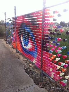 the fence is decorated with colorful paper cups