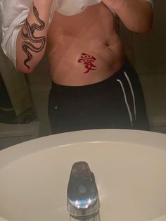 a man with a snake tattoo on his chest is taking a selfie in the mirror