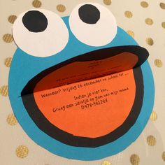 a paper cut out of a cookie monster with eyes and mouth on a polka dot tablecloth