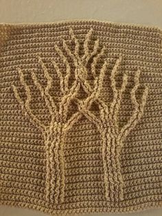 two crocheted trees are shown on the side of a knitted wall hanging