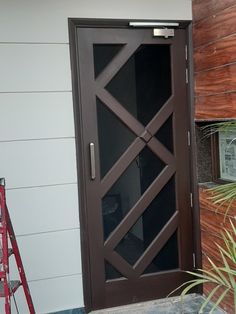 the front door to a house with a ladder next to it and a potted plant