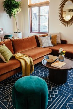 a living room filled with furniture and a large mirror on the wall above it's windows