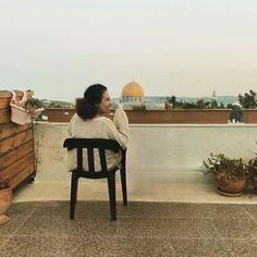 a woman sitting in a chair on top of a roof