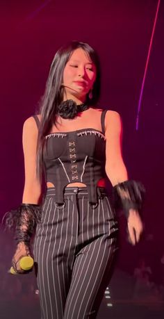 a woman with long black hair is on stage wearing striped pants and an elaborate corset