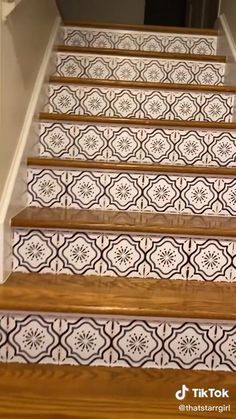 the stairs are decorated with black and white tile designs, along with wooden handrails