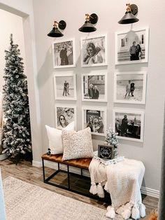 a living room with pictures on the wall and a bench in front of some christmas trees