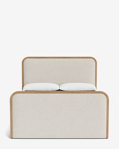 a bed with two pillows on top of it and a wooden frame around the headboard