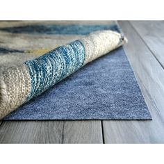 a blue rug on top of a wooden floor next to a gray and white rug