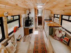 an interior view of a tiny home with wood flooring and white couches, windows, and rugs