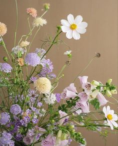 a vase filled with lots of different flowers on top of a table next to a wall