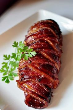 bacon - brown sugar pork tenderloin on a white plate with parsley