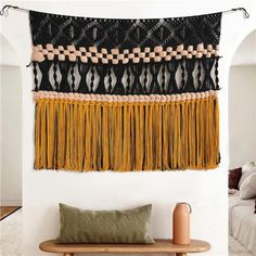 the wall hanging is decorated with black and yellow tassels