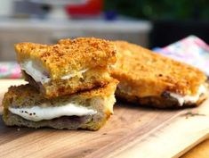 two grilled sandwiches sitting on top of a wooden cutting board