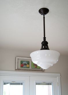 a light fixture hanging from the ceiling in a room with two doors and window frames