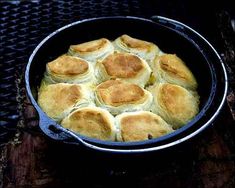 a pan filled with food sitting on top of a wooden table next to a grill