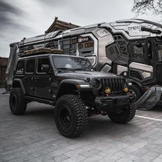 two jeeps parked next to each other in a parking lot with an rv behind them