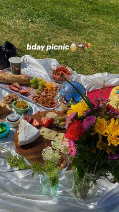 a picnic is set out on the grass with food and drinks laid out in front of it