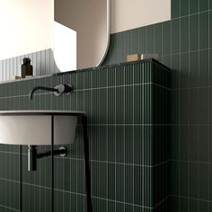 a sink and mirror in a room with green tiles on the walls, along with a black towel rack