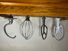 four kitchen utensils hanging on a wall