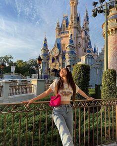 a woman standing next to a metal fence near a castle