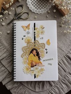 a notebook with an image of a woman surrounded by flowers, scissors and other items