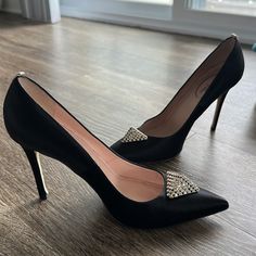 a pair of black high heeled shoes sitting on top of a wooden floor