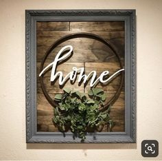 a wooden sign that says home with some greenery in front of it on a wall