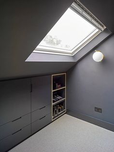 an attic bedroom with skylight and storage cabinets