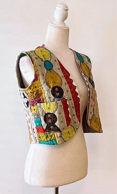 a white mannequin wearing a multicolored vest on top of a dress form