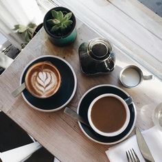 two cups of coffee on a table with silverware