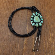 Vintage turquoise and sterling silver bolo tie. The center stone is 25mm tall. 12 turquoise stones surround the center stone. They vary in color from green to blue and in shape. There are silver balls between the stones. The whole face of the bolo measures 2 3/8" long by 1 7/8" wide. The cord and tips are 44" long. It is stamped sterling with an unknown artist's hallmark (GM). The bolo is beautiful and in good condition. Thank you for shopping in our store. Please let us know if you have questio Green To Blue, Turquoise Stones, Tucson Az, Vintage Turquoise, Tie Accessories, Green Turquoise, Suit And Tie, Turquoise Stone