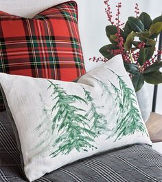 two pillows on a couch with christmas decorations in the back and plaid pillow cases behind them