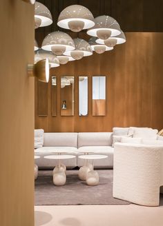 a living room filled with white furniture and lots of round lights hanging from the ceiling