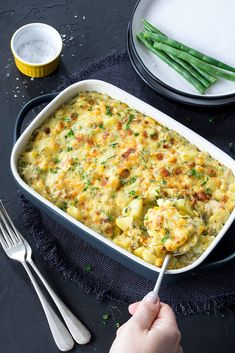 a casserole dish with potatoes and green beans in it on a black surface