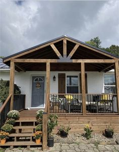 a small white house with wooden steps leading up to the front door and covered porch