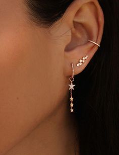 a woman's ear with two stars hanging from the middle and one star dangling from the side