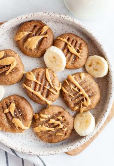 cookies with peanut butter and bananas on a plate next to a glass of milk in the background