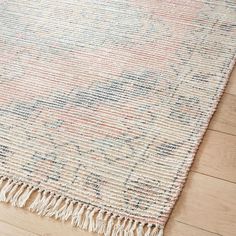 an area rug with fringes on the floor and wood floors in front of it