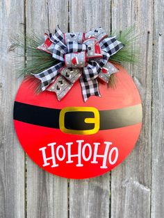 a christmas ornament hanging on the side of a wooden fence with a bow