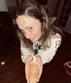 a woman is holding up a piece of bread in one hand and smiling at the camera