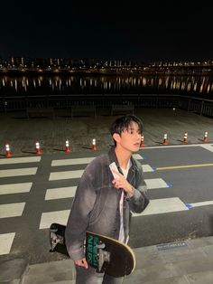 a young man holding a skateboard on top of a parking lot