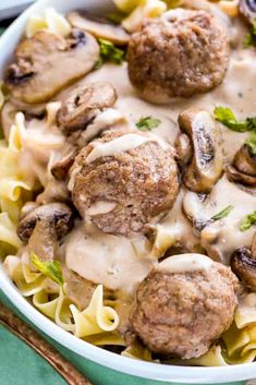 a bowl filled with pasta and meatballs covered in gravy, mushrooms and broccoli