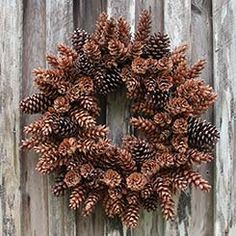 a wreath made out of pine cones hanging on a wooden fence