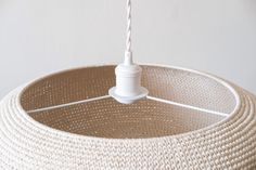 a white lamp hanging from the ceiling with a cord attached to it's end