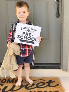 a young boy holding a sign that says first day pre - school with a teddy bear