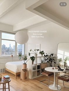 a bedroom with a bed, desk and chairs next to a large window overlooking the city