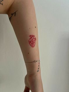 a woman's arm with a red heart tattoo on the left side of her arm