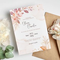 a wedding card with flowers on it next to some envelopes and paper napkins