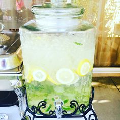 a glass jar filled with lemonade sitting on top of a table next to a metal rack